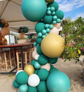 Une guirlande organique fixée au barnum de ce bar de plage. Quelques composition de bouquets de ballons en arrière plan harmonie l’espace alloué de la fête.